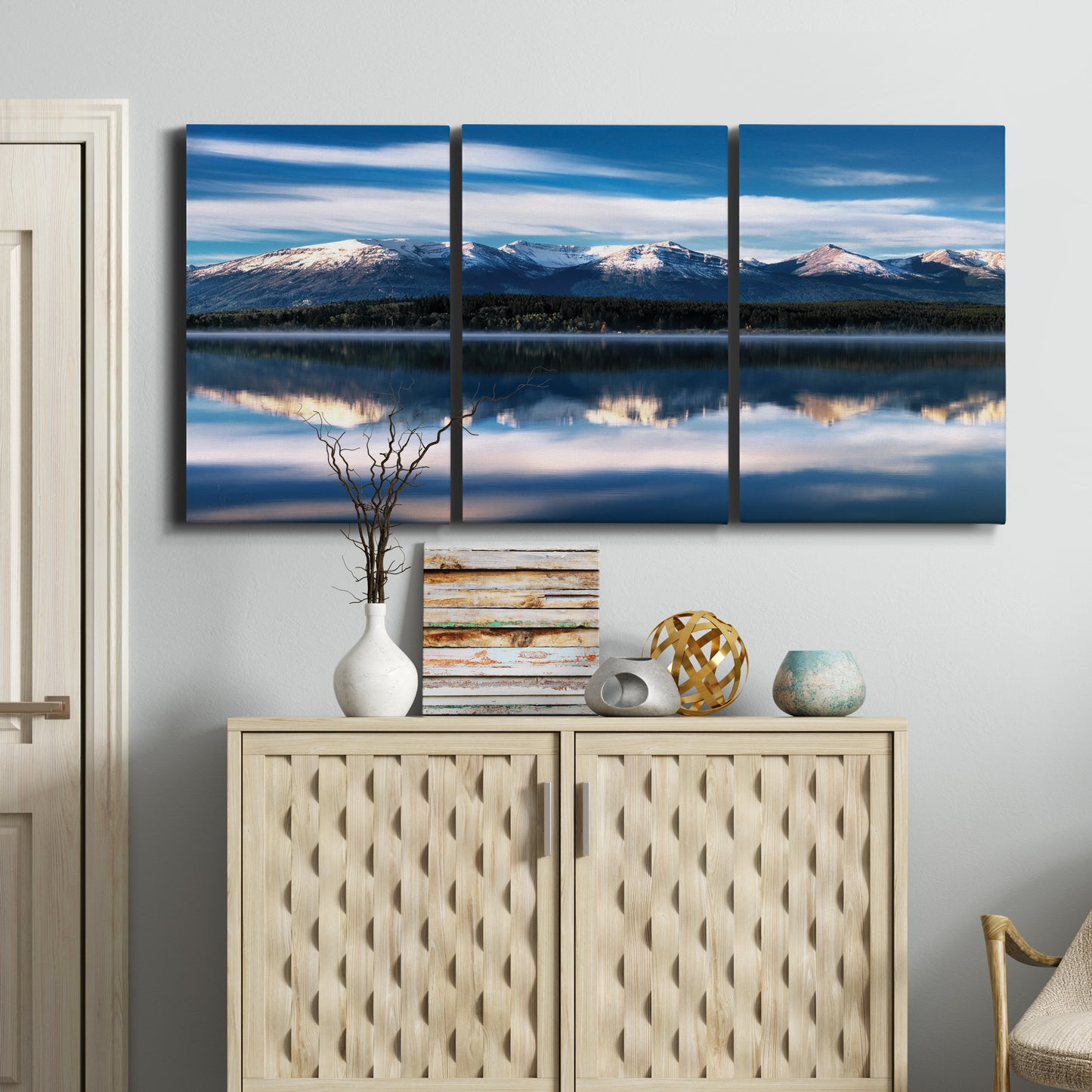 Three-panel canvas wall art featuring calm lake beneath mountains photograph, displayed above a cabinet in an entryway.