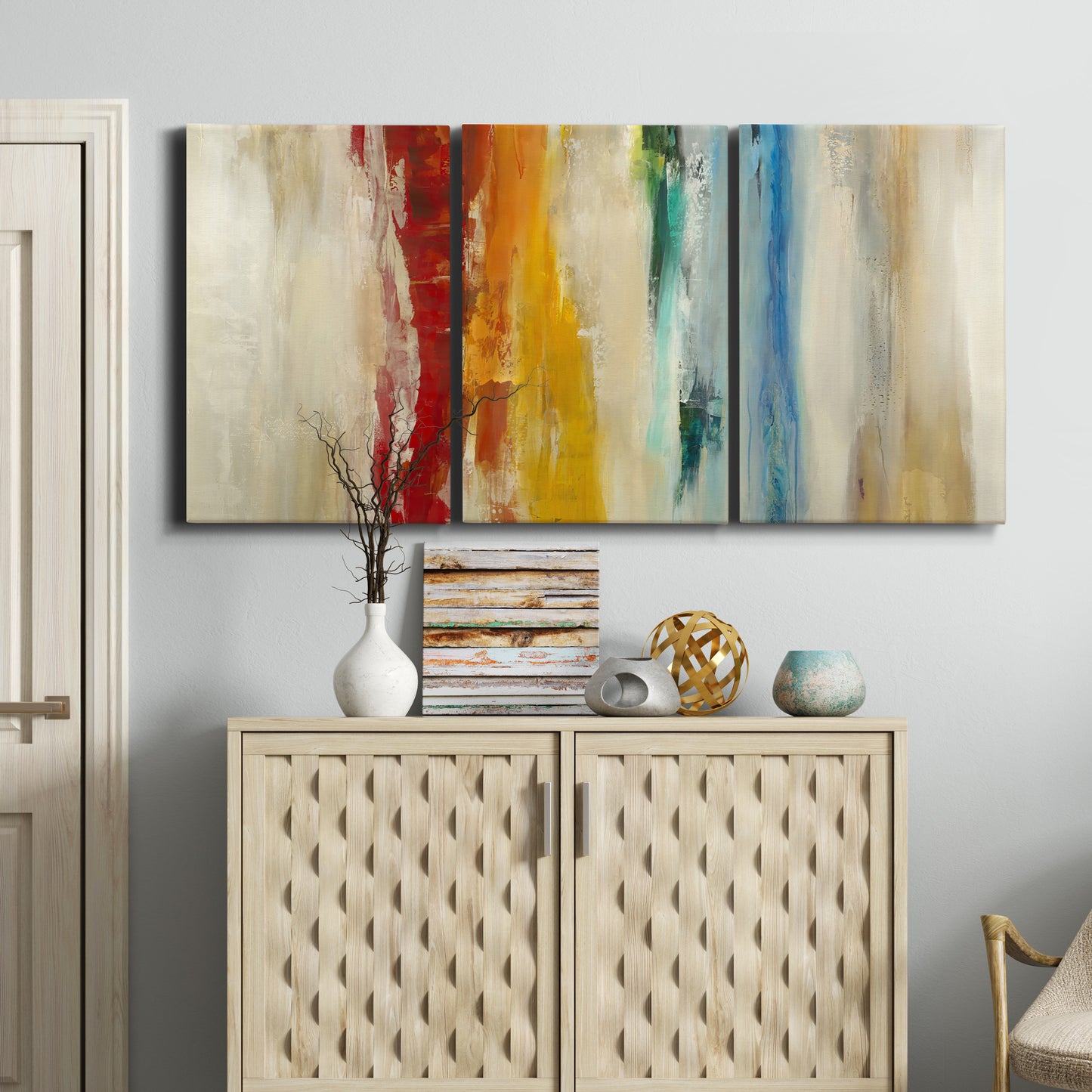 Three-panel canvas wall art featuring abstract divided color hemisphere forms, displayed above a cabinet in an entryway.