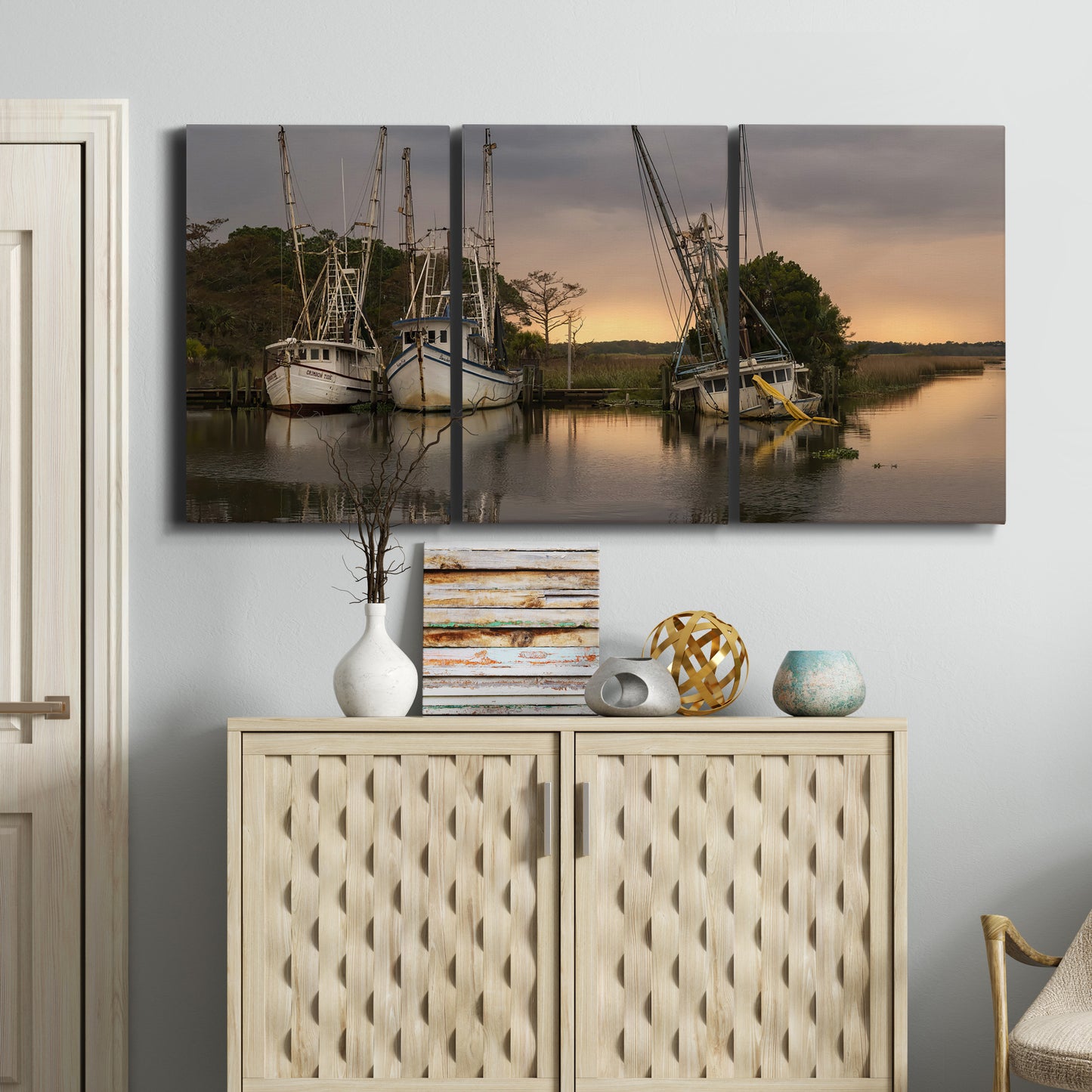 Three-panel canvas wall art featuring fishing trawlers on working harbor, displayed above a cabinet in an entryway.