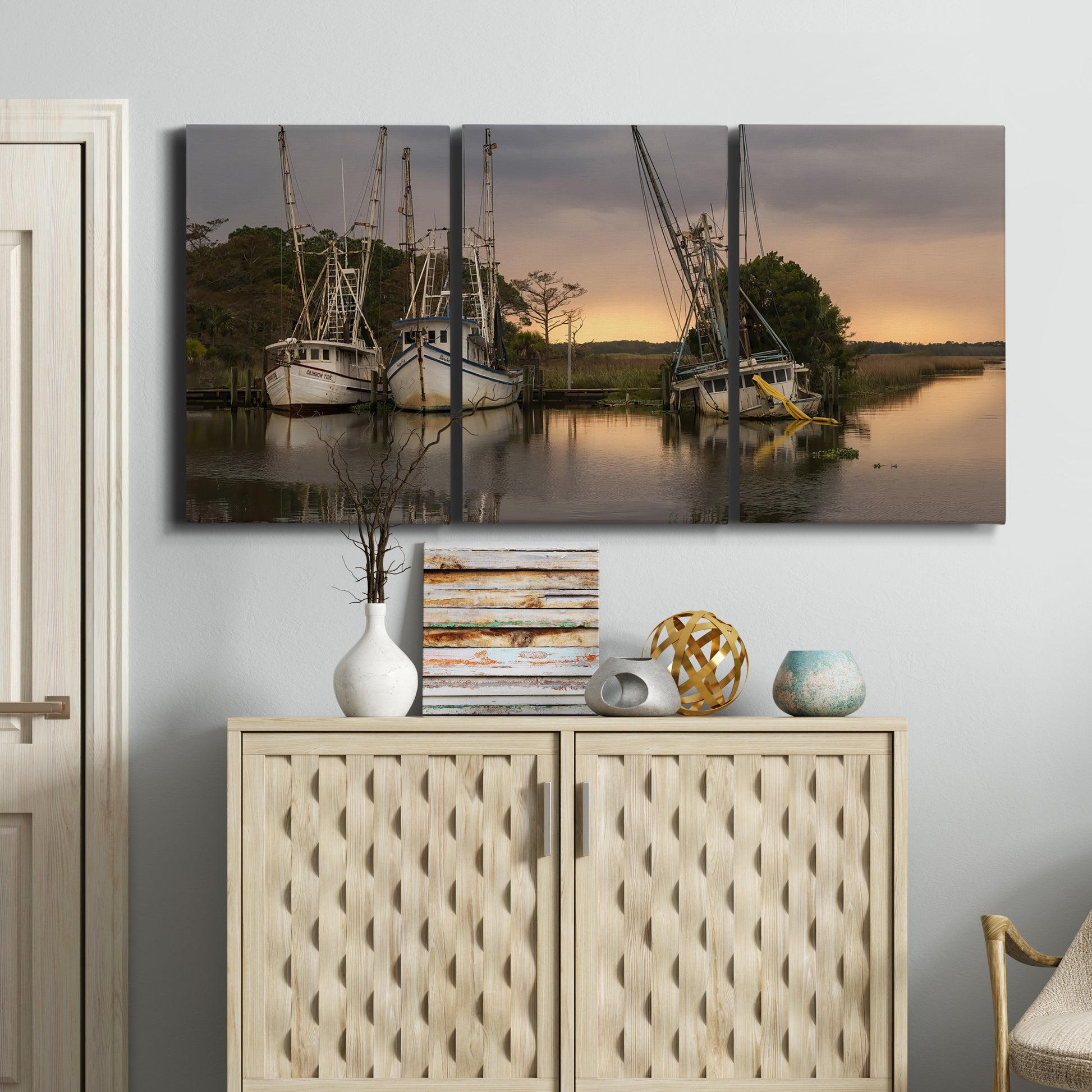 Three-panel canvas wall art featuring fishing trawlers on working harbor, displayed above a cabinet in an entryway.