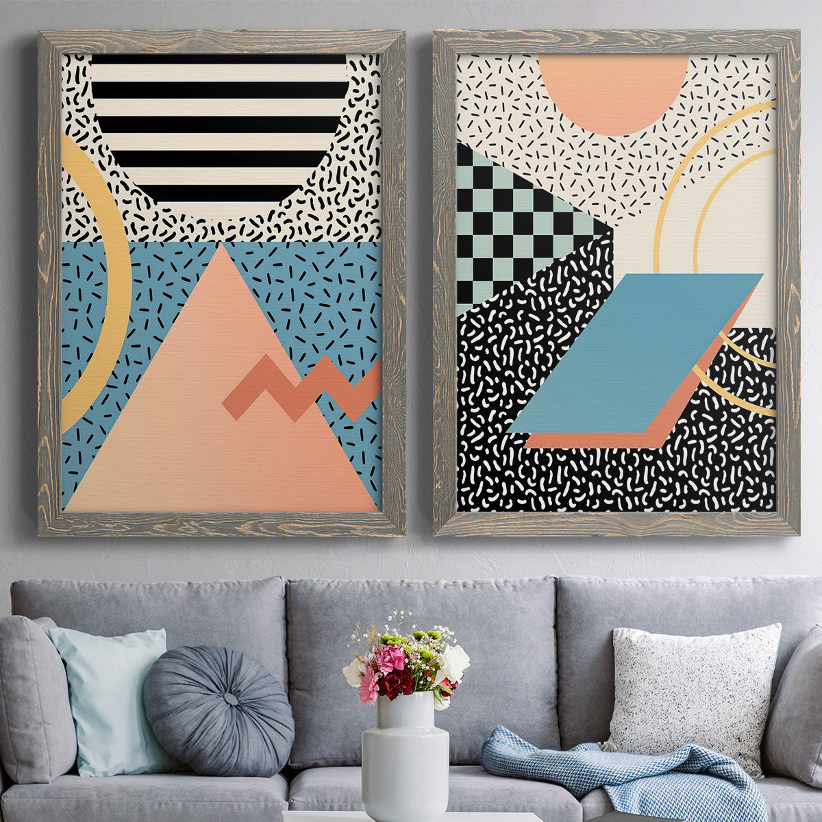 Set of two gray barnwood framed canvas prints depicting paired retro graphic abstracts with checkerboards stripes squiggles peach blue black and mint shapes above a sofa in a contemporary living room.