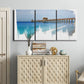 Three-panel canvas wall art featuring coastal pier extending over water, displayed above a cabinet in an entryway.