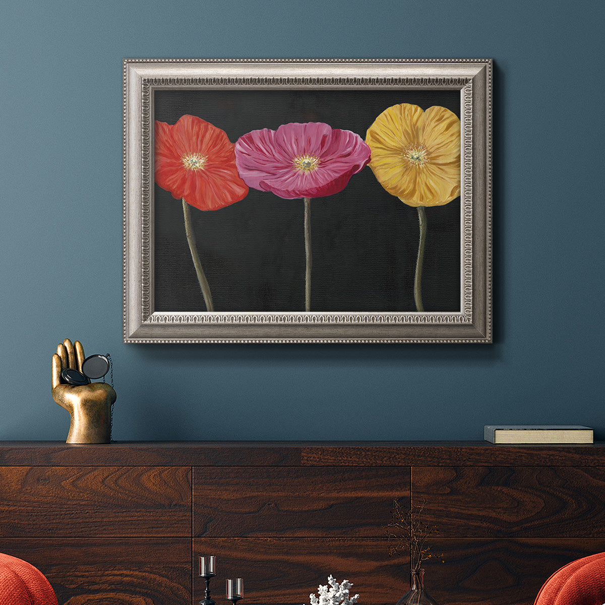 Contemporary poppy flower artwork in an ornate vintage silver frame displayed in a dark-toned interior setting.