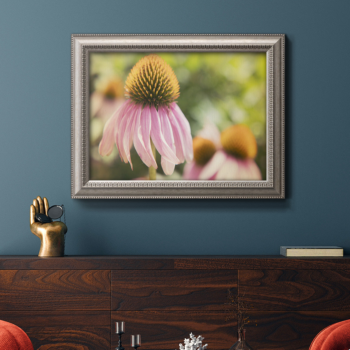 Close-up echinacea bloom photography in an ornate vintage silver frame displayed in a dark-toned interior setting.