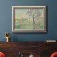 Classical watercolor landscape with trees in an ornate vintage silver frame displayed in a dark-toned interior setting.