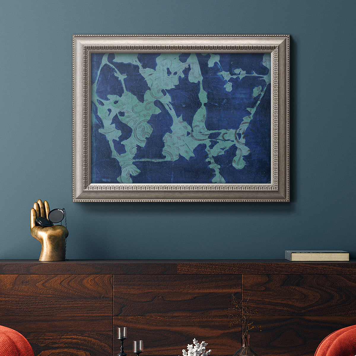 Blue abstract botanical in an ornate vintage silver frame displayed in a dark-toned interior setting.