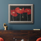 Modern red poppy floral artwork in an ornate vintage silver frame displayed in a dark-toned interior setting.