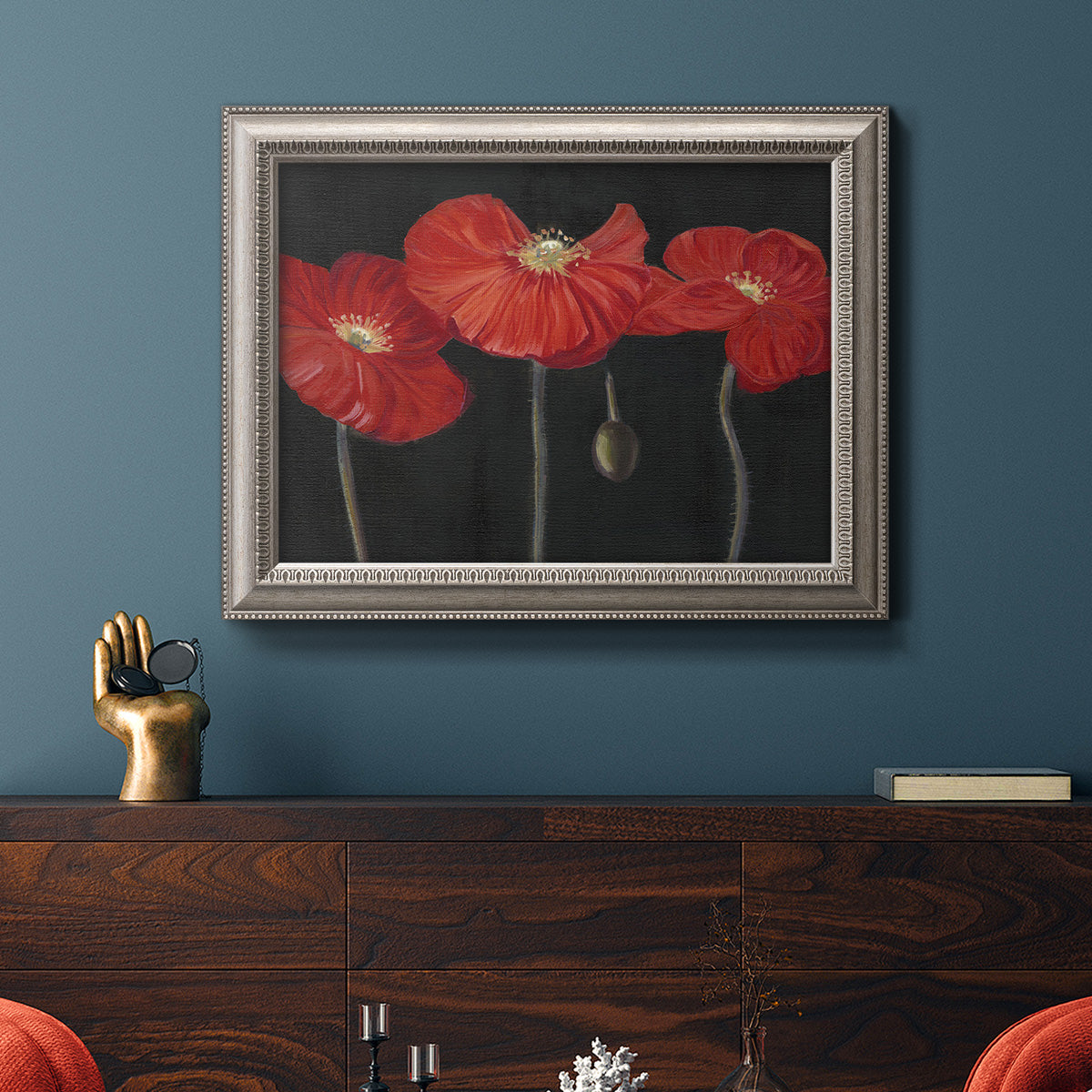 Modern red poppy floral artwork in an ornate vintage silver frame displayed in a dark-toned interior setting.