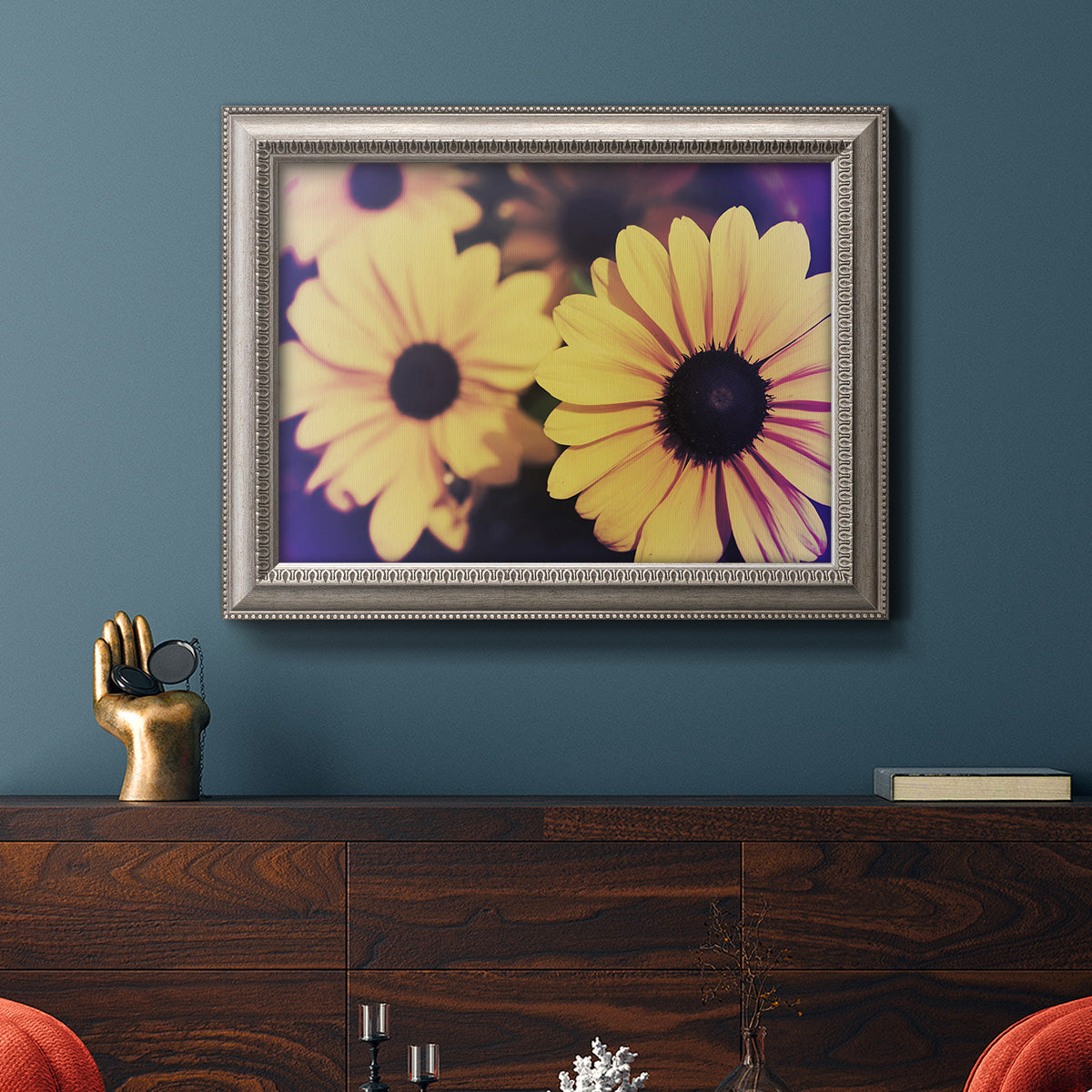 Contemporary yellow Susan floral photograph in an ornate vintage silver frame displayed in a dark-toned interior setting.