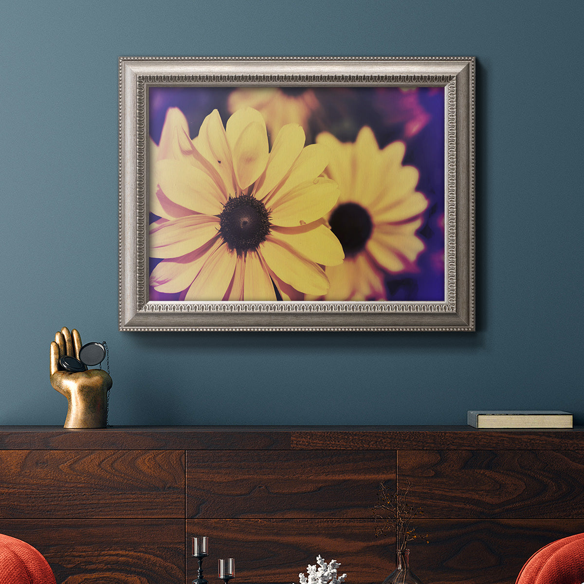 Bright black-eyed Susan flower photography in an ornate vintage silver frame displayed in a dark-toned interior setting.