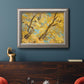 Vibrant yellow autumn leaves on branches in an ornate vintage silver frame displayed in a dark-toned interior setting.