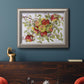 Classic still life painting of apples in an ornate vintage silver frame displayed in a dark-toned interior setting.