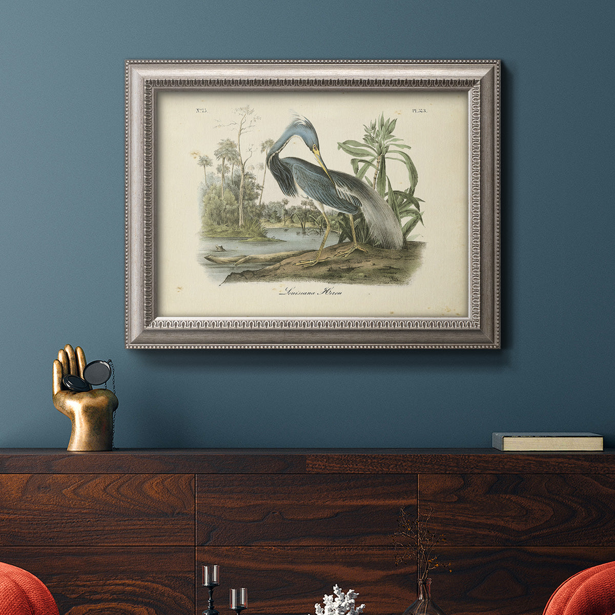 Antique Louisiana heron bird illustration by John James Audubon in an ornate vintage silver frame displayed in a dark-toned interior setting.