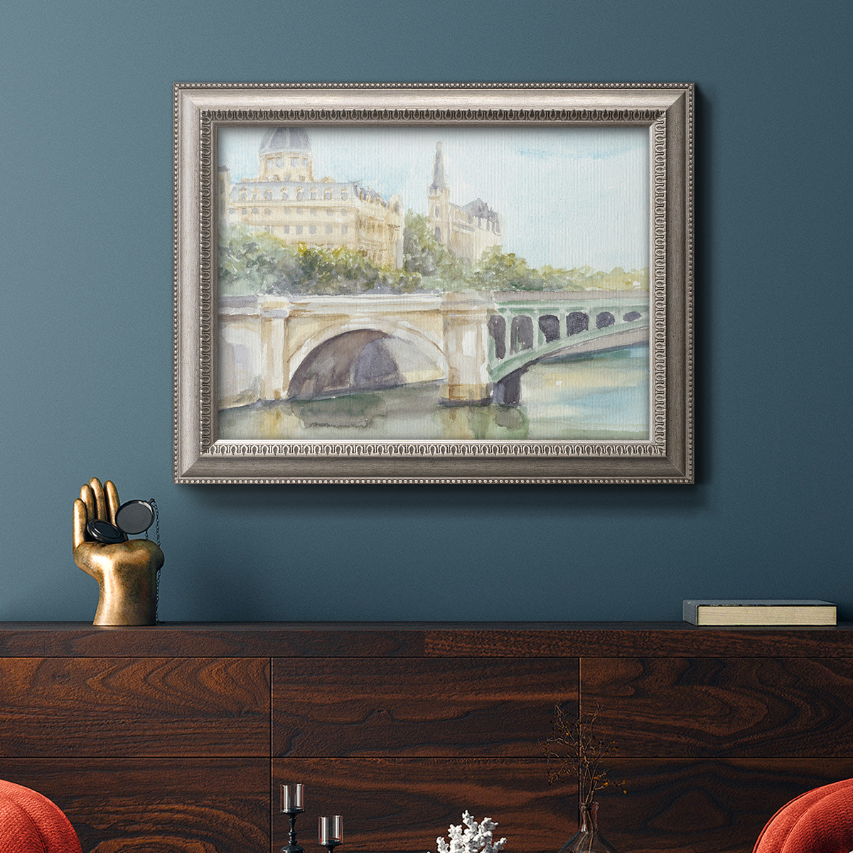 Classical watercolor painting of a French bridge in an ornate vintage silver frame displayed in a dark-toned interior setting.