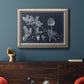 Antique botanical foliage illustration on navy background in an ornate vintage silver frame displayed in a dark-toned interior setting.
