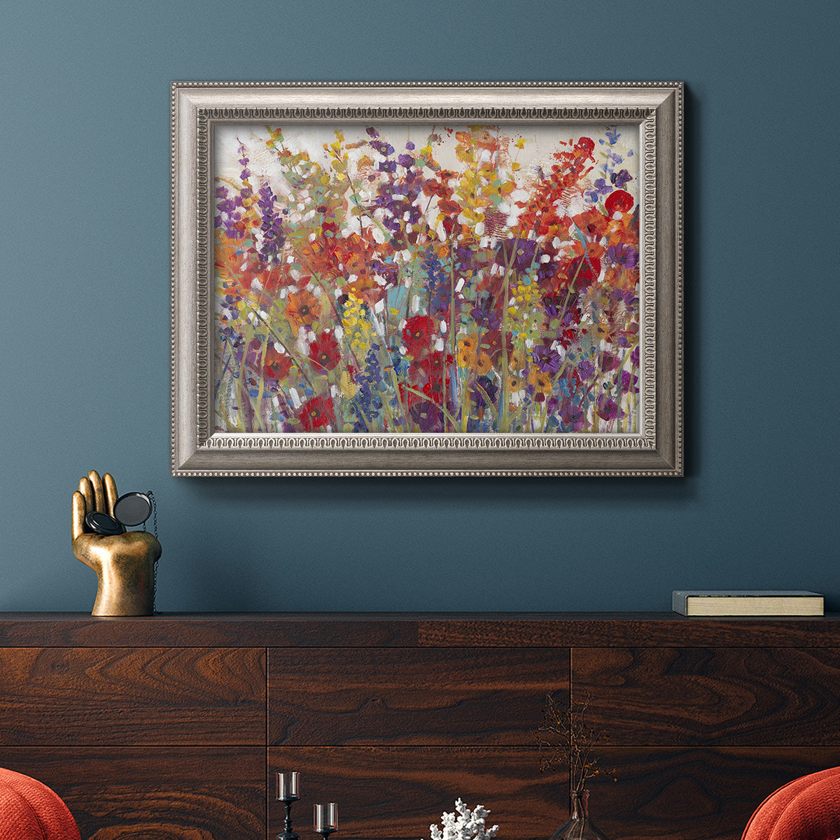 Impressionist floral bouquet artwork in an ornate vintage silver frame displayed in a dark-toned interior setting.