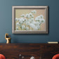 Delicate baby’s breath floral photograph in an ornate vintage silver frame displayed in a dark-toned interior setting.