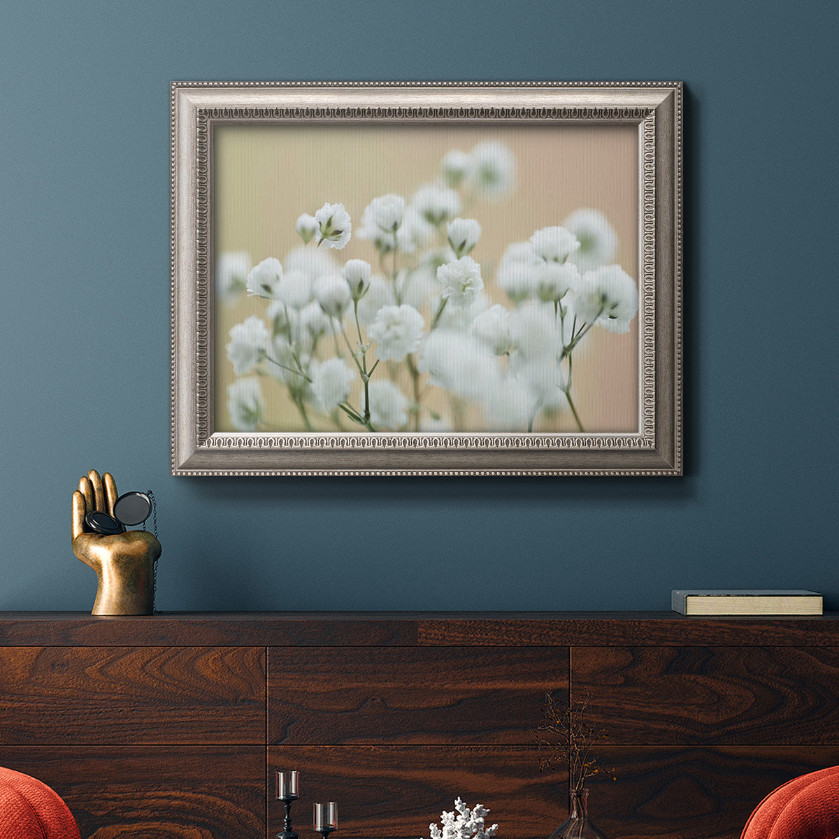 Delicate baby’s breath floral photograph in an ornate vintage silver frame displayed in a dark-toned interior setting.