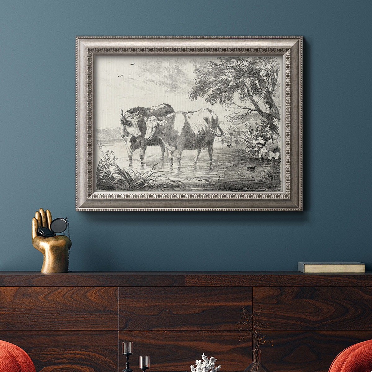 Classical countryside landscape artwork by Nicolas Berchem in an ornate vintage silver frame displayed in a dark-toned interior setting.