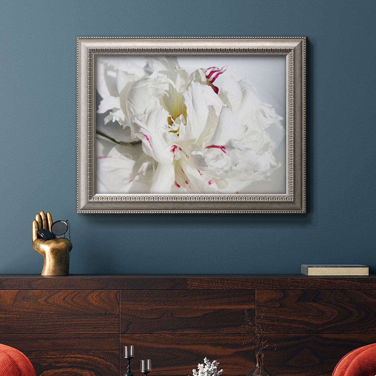 White peony close-up photography in an ornate vintage silver frame displayed in a dark-toned interior setting.