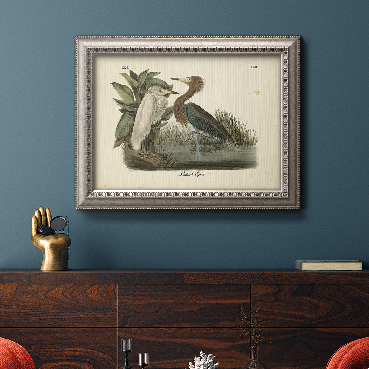 Antique reddish egret bird illustration by John James Audubon in an ornate vintage silver frame displayed in a dark-toned interior setting.