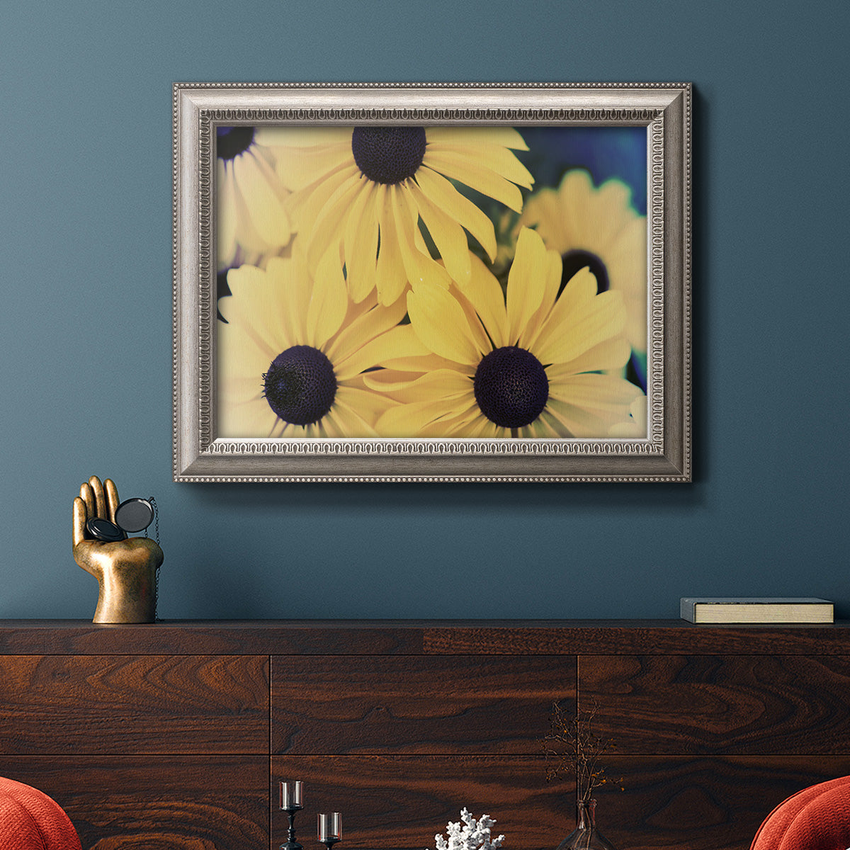 Modern sunflower-style Susan floral photograph in an ornate vintage silver frame displayed in a dark-toned interior setting.