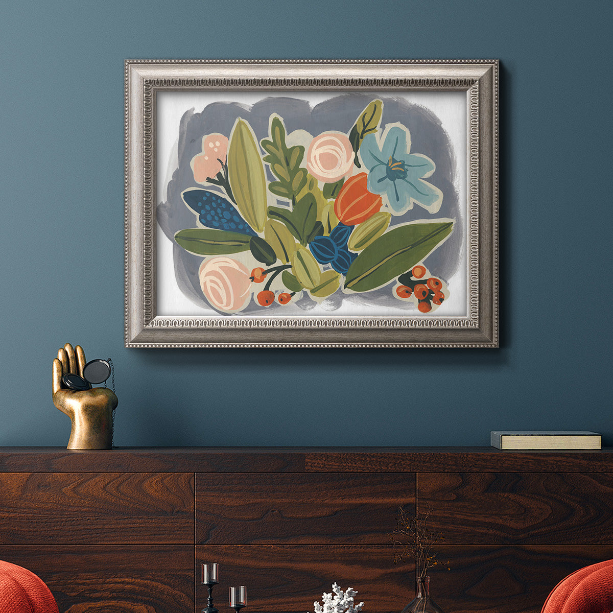 Colorful eclectic botanical artwork in an ornate vintage silver frame displayed in a dark-toned interior setting.