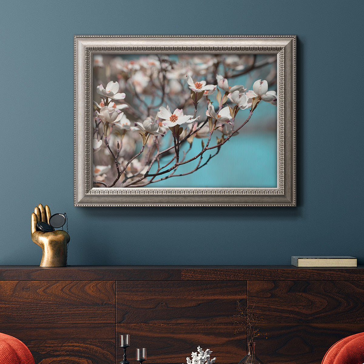 Color-rich dogwood floral photography in an ornate vintage silver frame displayed in a dark-toned interior setting.