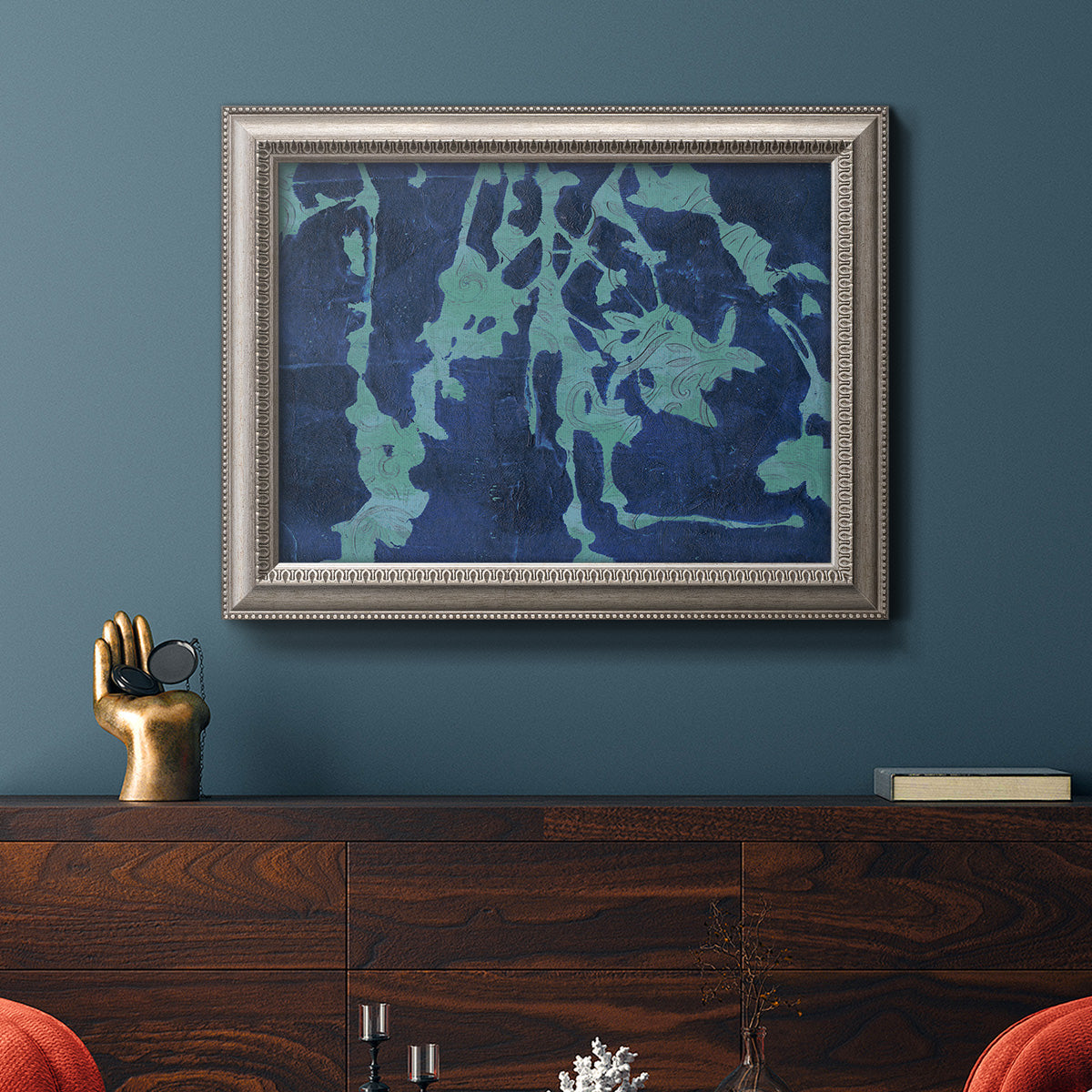 Industrial abstract botanical in an ornate vintage silver frame displayed in a dark-toned interior setting.