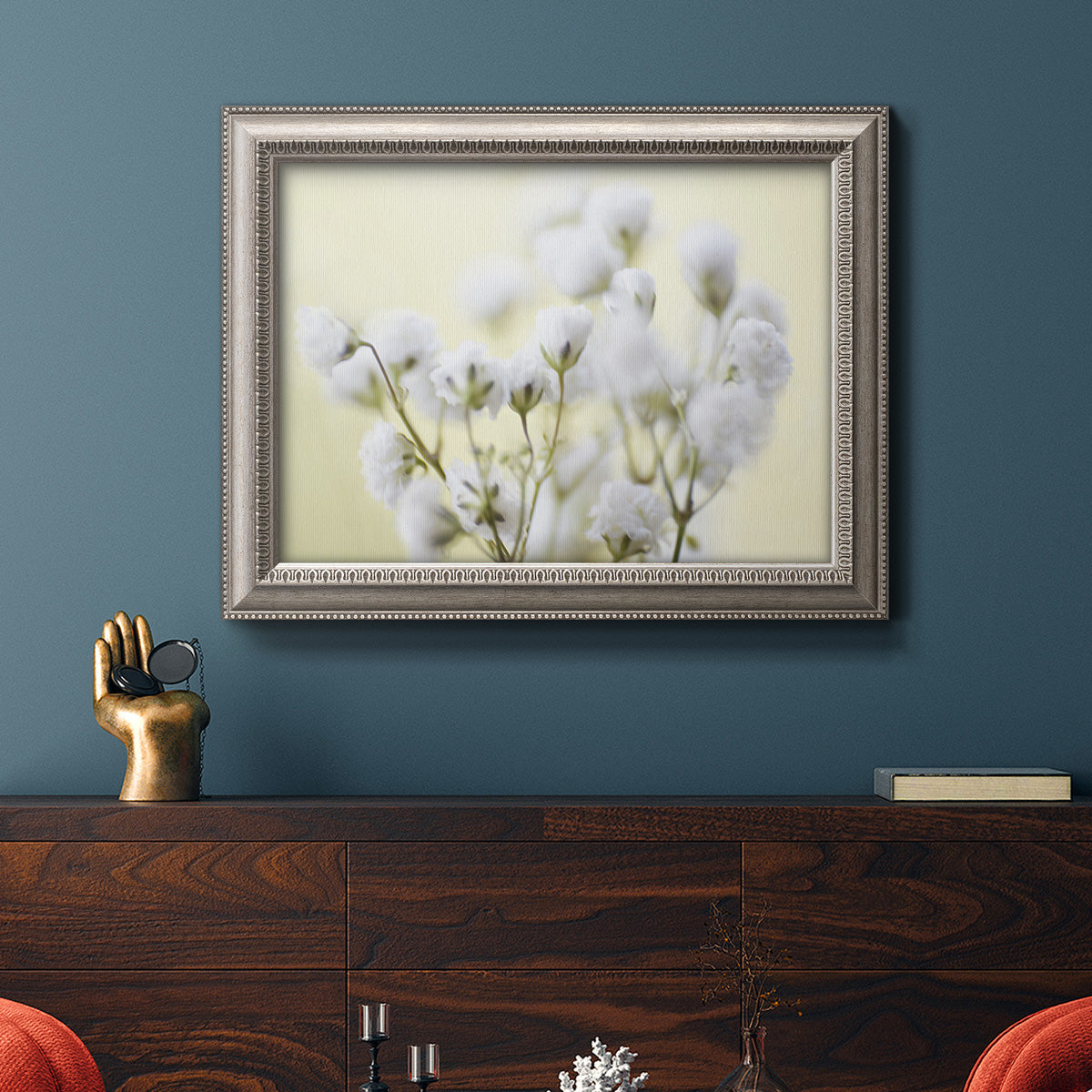 Soft-focus baby’s breath flower photograph in an ornate vintage silver frame displayed in a dark-toned interior setting.