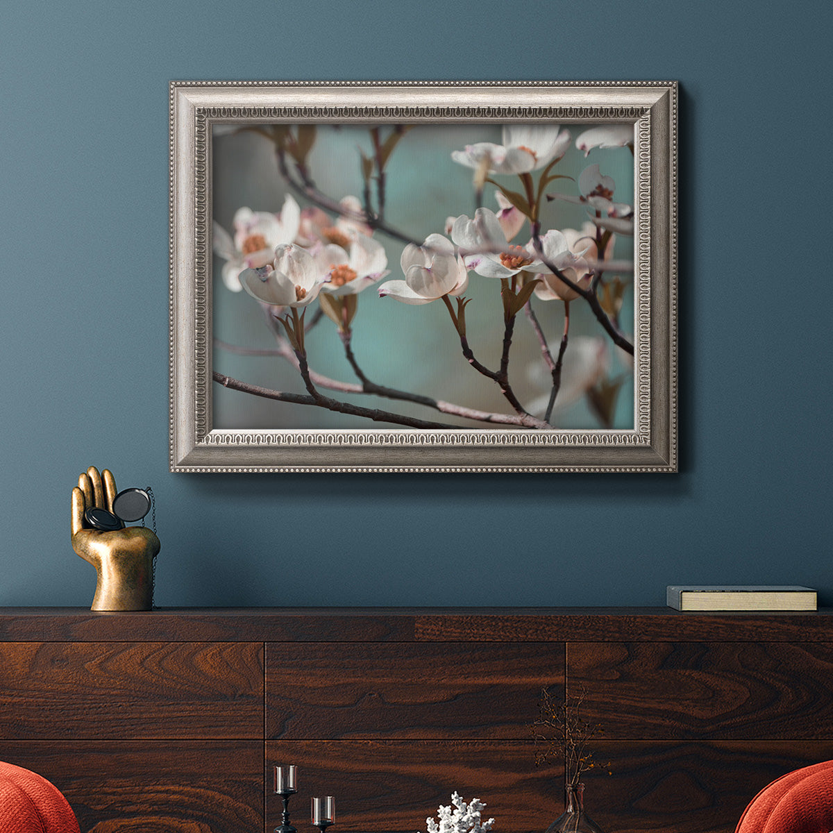 Close-up dogwood blossom photography in an ornate vintage silver frame displayed in a dark-toned interior setting.