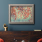 Eclectic fall floral landscape artwork in an ornate vintage silver frame displayed in a dark-toned interior setting.