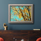 Bright autumn leaves against a blue sky in an ornate vintage silver frame displayed in a dark-toned interior setting.