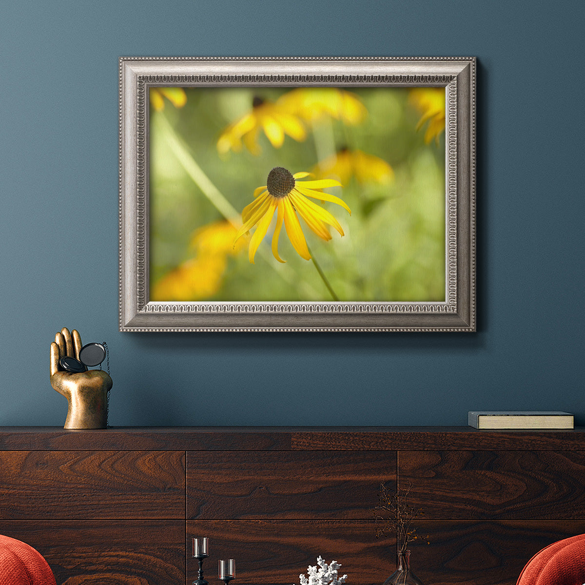 Contemporary black-eyed Susan flower photography in an ornate vintage silver frame displayed in a dark-toned interior setting.
