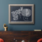 Vintage botanical foliage illustration on navy background in an ornate vintage silver frame displayed in a dark-toned interior setting.