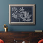 Antique botanical foliage artwork on navy background in an ornate vintage silver frame displayed in a dark-toned interior setting.