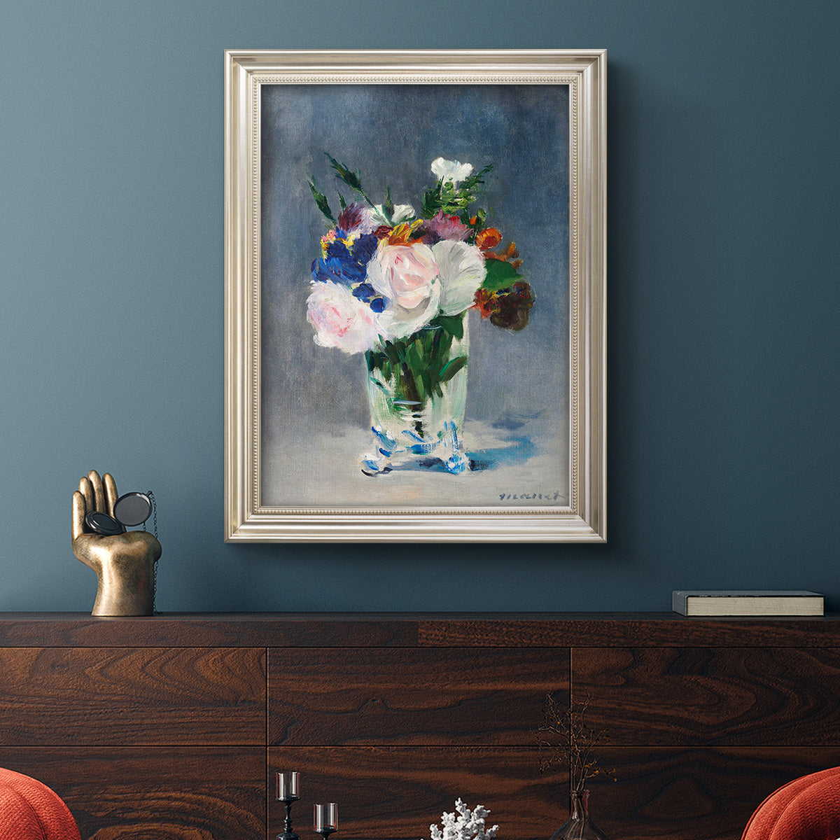 Impressionist floral still life painting by Claude Monet in an ornate champagne frame displayed in a dark-toned interior setting.