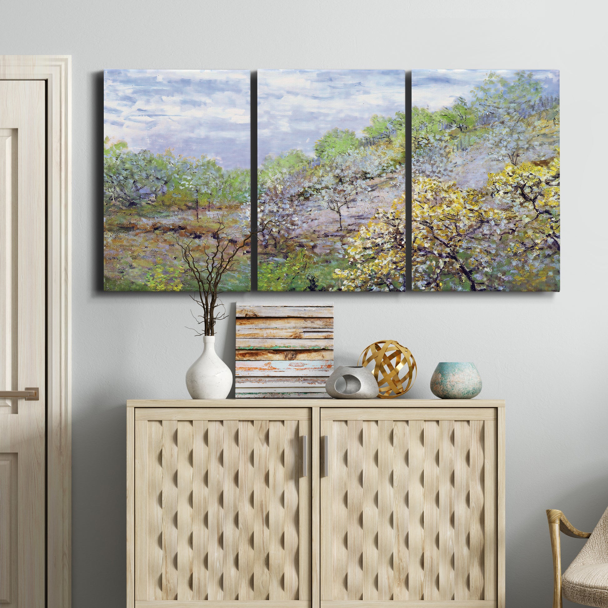 Three-panel canvas wall art featuring spring orchard in full bloom, displayed above a cabinet in an entryway.