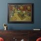 Impressionist interior of a night café by Vincent van Gogh in an ornate black frame with gilded inner detail displayed in a dark-toned interior setting.