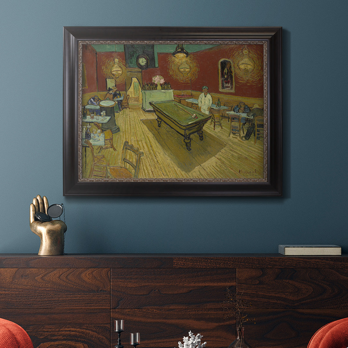Impressionist interior of a night café by Vincent van Gogh in an ornate black frame with gilded inner detail displayed in a dark-toned interior setting.