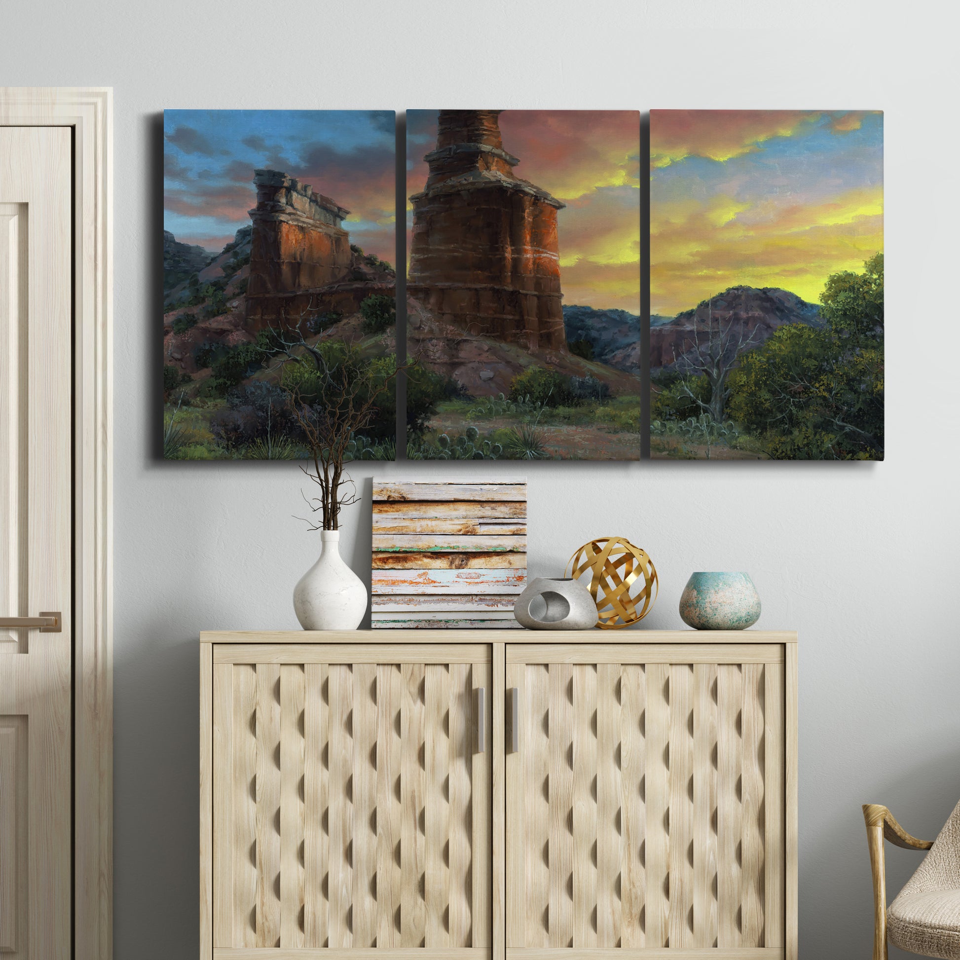 Three-panel canvas wall art featuring dramatic canyon landscape at dusk, displayed above a cabinet in an entryway.