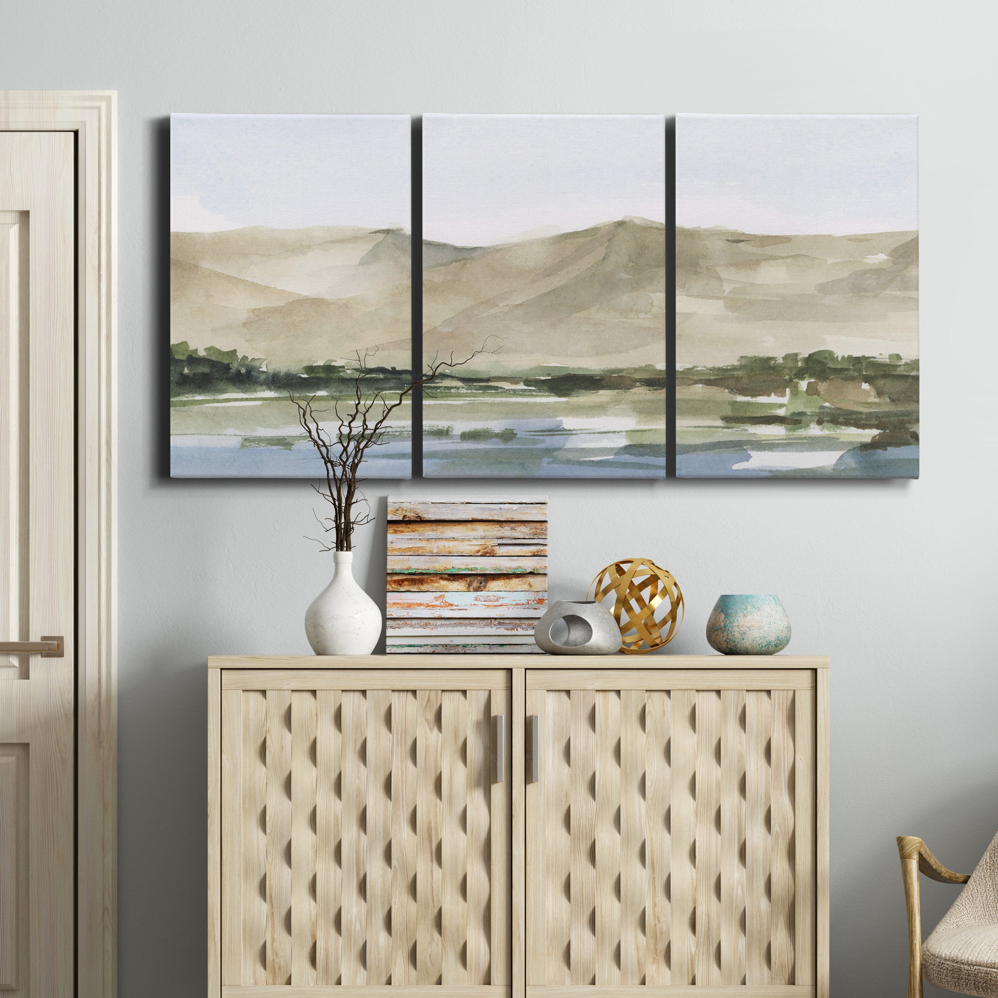 Three-panel canvas wall art featuring desert mountain landscape watercolor, displayed above a cabinet in an entryway.