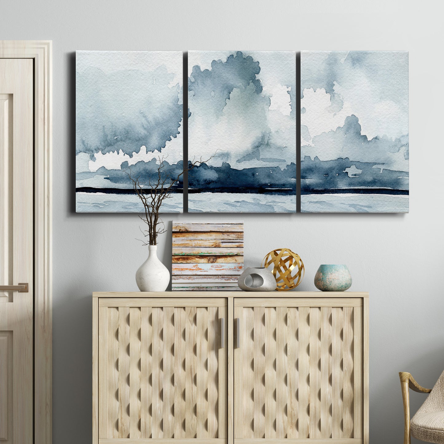 Three-panel canvas wall art featuring abstract rainstorm watercolor, displayed above a cabinet in an entryway.