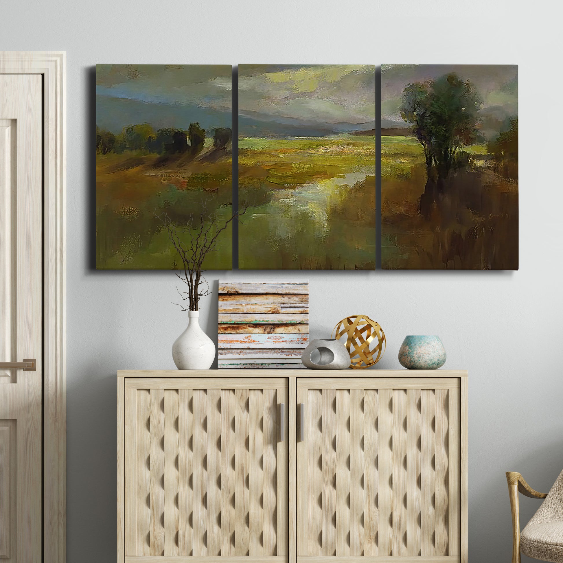 Three-panel canvas wall art featuring winding rural road through countryside, displayed above a cabinet in an entryway.
