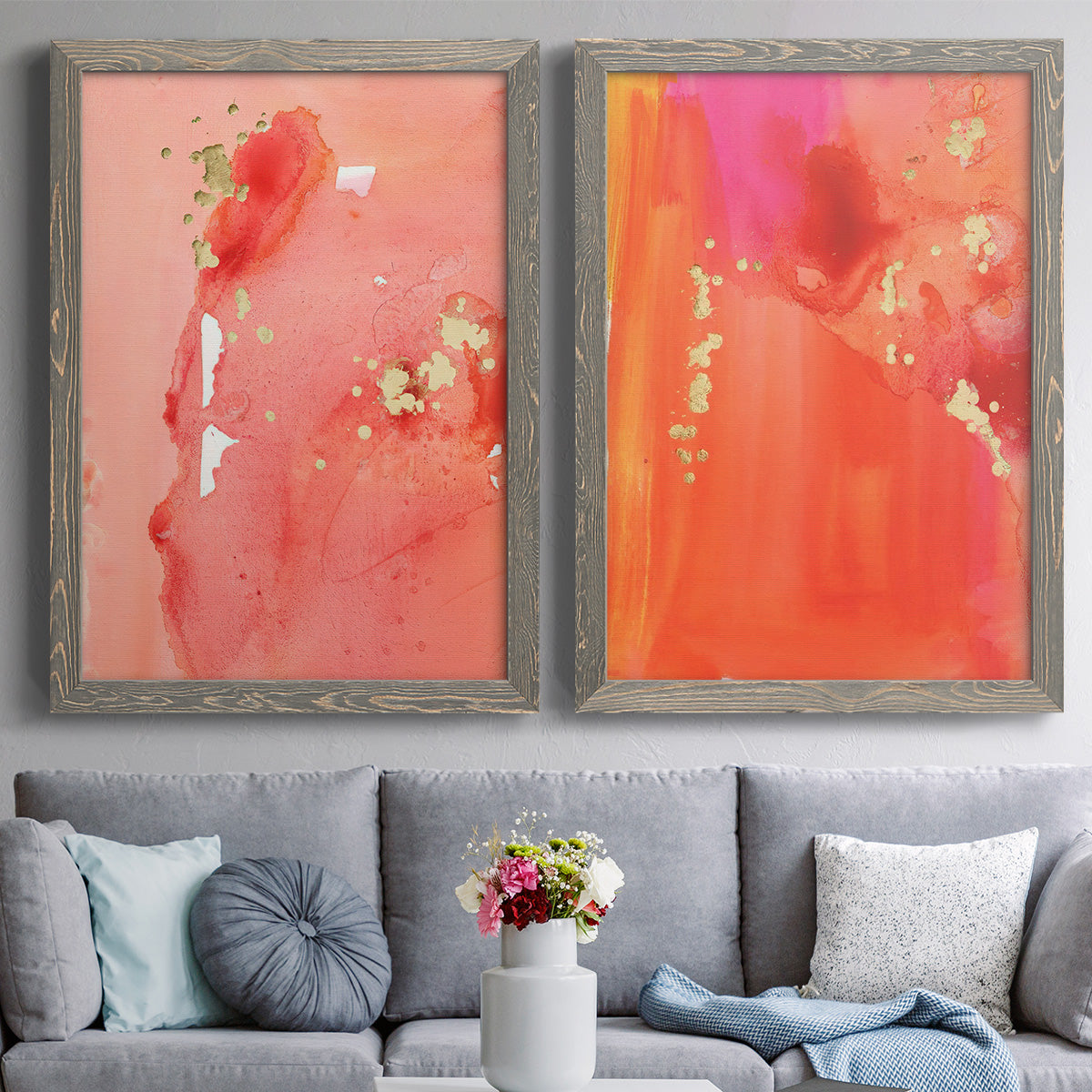 Set of two gray barnwood framed canvas prints depicting paired glamorous fluid abstracts with translucent warm washes, drips, and scattered metallic accents above a sofa in a contemporary living room.