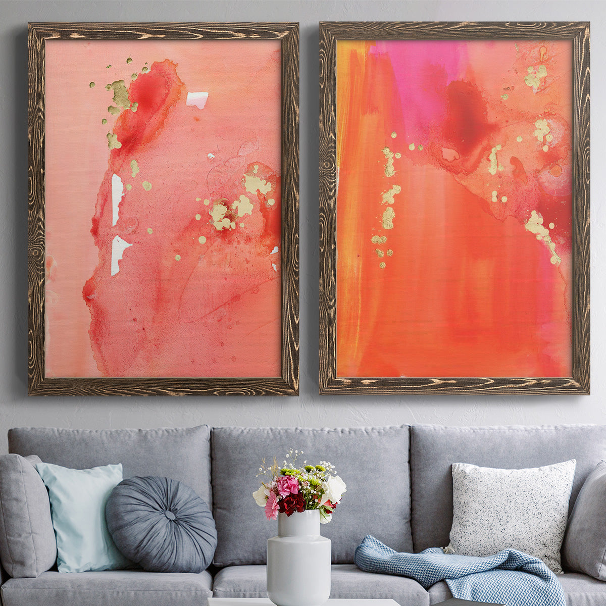 Set of two walnut barnwood framed canvas prints depicting paired glamorous fluid abstracts with translucent warm washes, drips, and scattered metallic accents above a sofa in a contemporary living room.