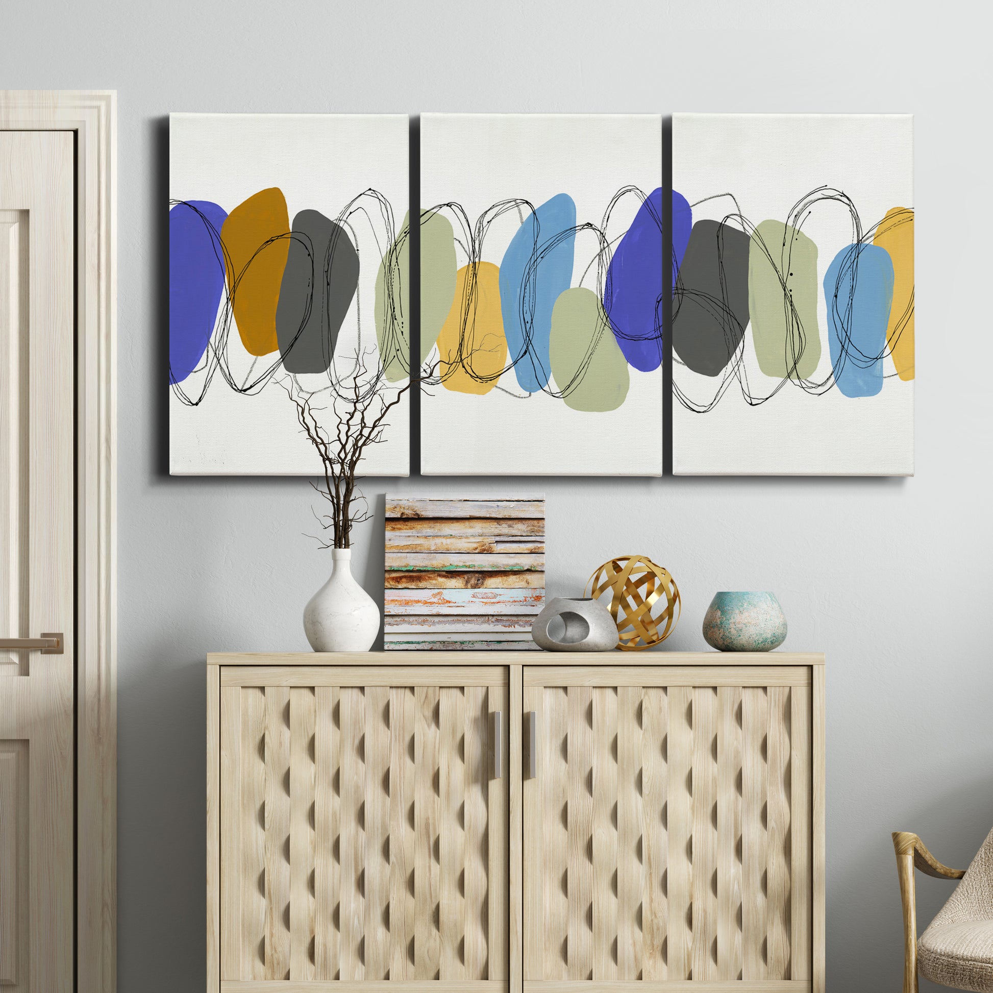 Three-panel canvas wall art featuring minimalist geometric abstract spacing, displayed above a cabinet in an entryway.