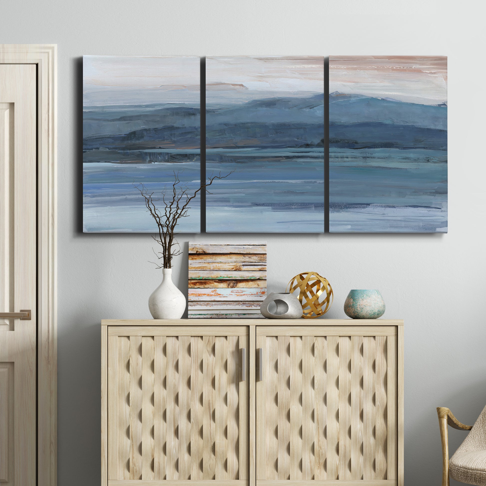 Three-panel canvas wall art featuring wide lake with distant shoreline, displayed above a cabinet in an entryway.