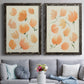 Set of two black barnwood framed canvas prints depicting paired airy watercolor floral paintings with soft petals, thin black stems, and warm cream backgrounds above a sofa in a contemporary living room.
