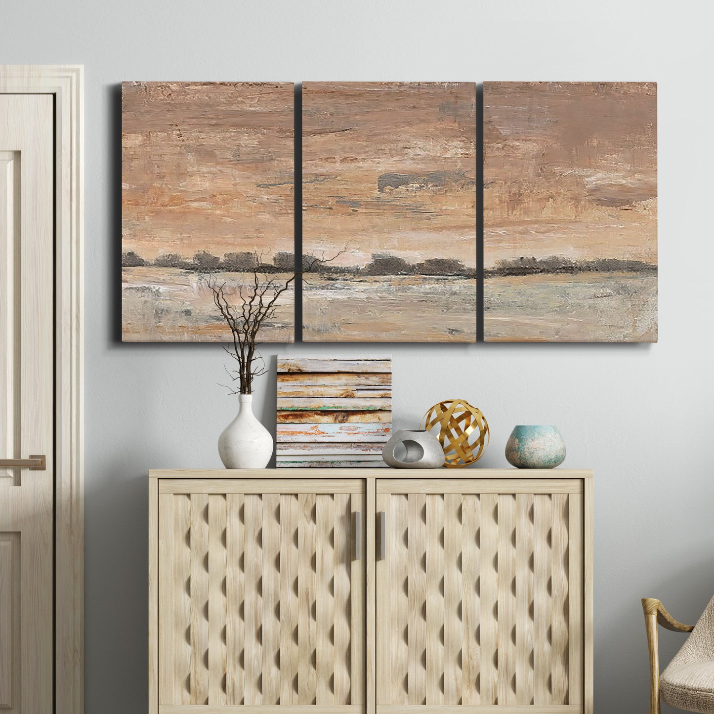 Three-panel canvas wall art featuring soft early evening landscape light, displayed above a cabinet in an entryway.
